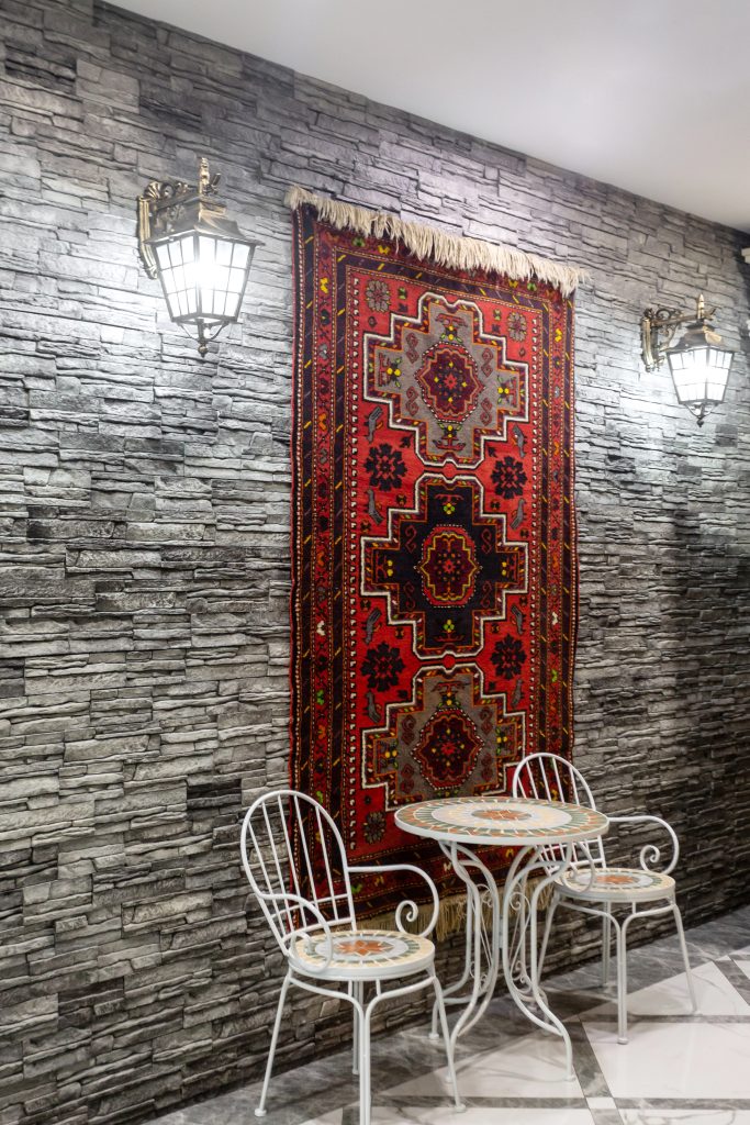 restaurant hall with grey stone wall decorated with azerbaijani carpet